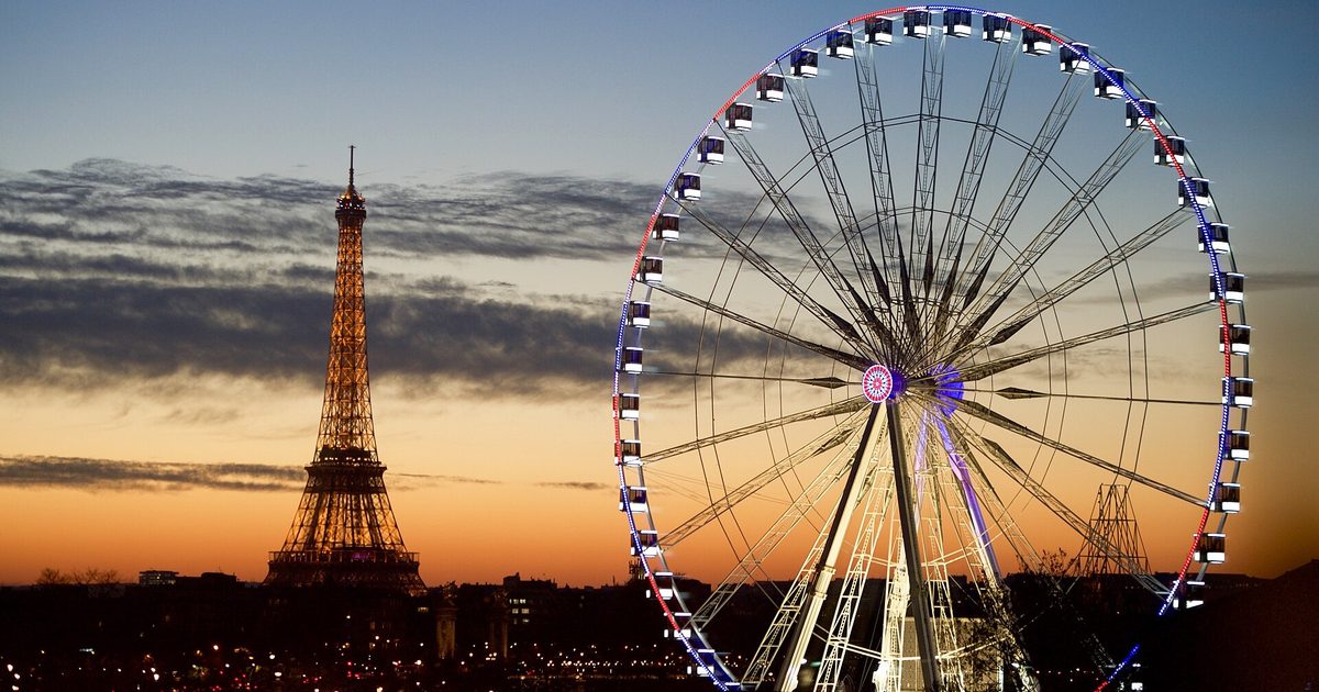 Evening view over Paris rooftops with the Eiffel Tower and a lit Ferris wheel on the Place de la Concorde