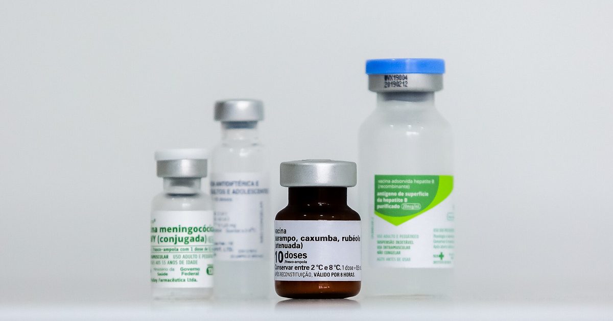 Four labeled vaccine vials of different sizes standing on a white table