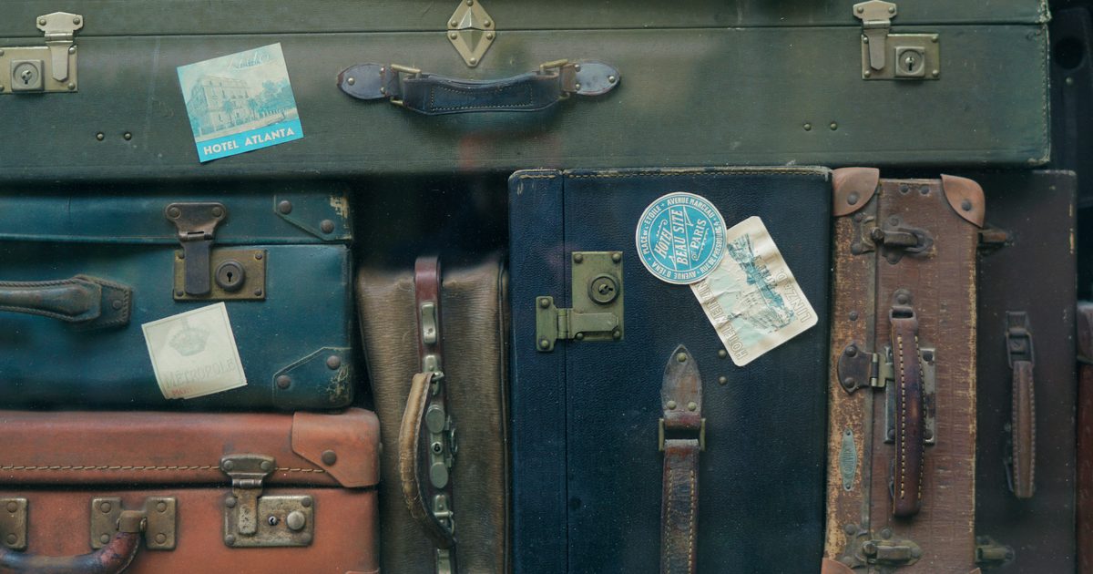 Stack of worn vintage leather suitcases covered in old travel stickers